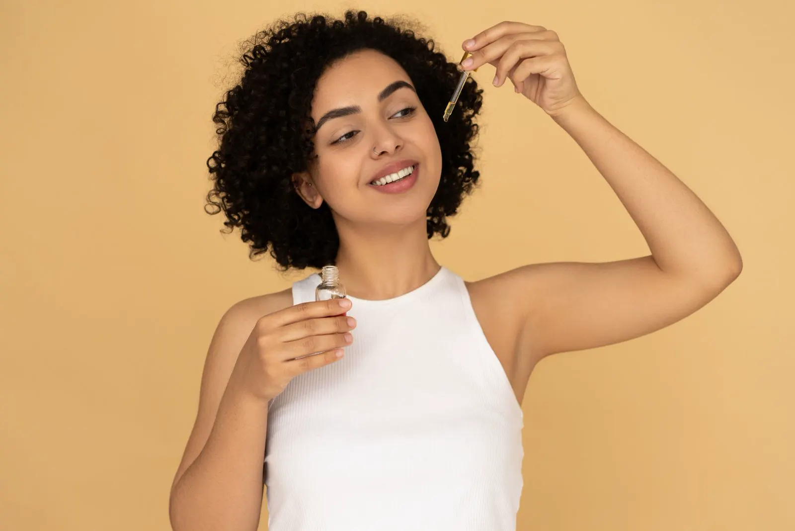 Femme aux cheveux bouclés appliquant une huile sur ses cheveux